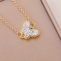 Macro detail of golden butterfly necklace with silver glitter inlay on pink jewelry box - White