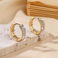 Nahaufnahme goldener Creolen mit doppelreihigen Diamanten auf Steinuntergrund - Goldene runde Creolen