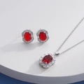 Elegant silver jewelry set with oval red gemstones and zircons on a round white stand - Silver Oval Red (HQ0001(15))