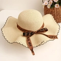 Detail of beige straw hat with wavy brim edge and brown bow ribbon decoration - Beige