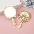 Specchio a mano dorato con rilievo di rosa vintage su un elegante sfondo rosa - Oro placcato