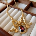 Detail of a vintage gold necklace with dark red gemstone and rope chain in a jewelry box - 28# Necklace - Gold - Red Gemstone Bow