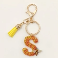 Close-up of letter S honeycomb acrylic keychain with yellow tassel and lobster clasp - Letter S