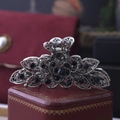 Detailed close-up of a silver floral hair claw with sparkling deep blue rhinestones - Ink Blue Rhinestone