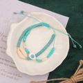 Detail of turquoise beaded bracelets with shell and evil eye charms in a shell dish - Style 17-Double Shell Eye Set