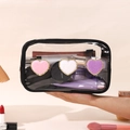 Transparent PVC makeup bag with embroidered heart patches and black trim held by hand - Black Heart