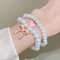 Close-up of beaded bracelets with pink bow and heart charms on a woman's wrist - 10 Pink Bow Heart (2623)