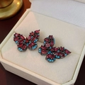 Detail of butterfly earrings with ruby red zircon and sky blue stones on black gold base - Red and Blue Butterfly Stud Earrings