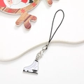Macro shot of white metal ice skate charm with black lace details and silver lobster clasp - Ice Skates / Silver