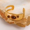 Close-up of golden hollow oval bracelet featuring amber-colored stones on a natural rock base - Tiger Eye Style Bracelet (WG-1308)