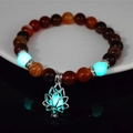 Detailed view of luminous beads and metallic lotus charm on a beaded yoga bracelet - 8mm Natural Coffee Agate with Blue-Green Light