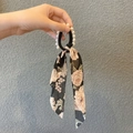 Detail eines Blumen-Seidenschal-Haargummis mit Kunstperle und schwarzem Gummiband - Schwarz