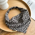 Close-up of black floral headband with white daisy pattern on a wooden tray - Black