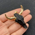 Ciondolo a forma di testa di toro dorata con dettagli neri tenuto in mano per misura - Stile Contrasto Nero e Oro (No.1)