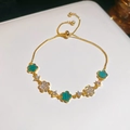 Detail van verstelbare gouden armband met klaverbedeltjes van malachiet en witte zirkoon - Groene Zirconia Bloem