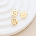 Macro shot of gold-plated square G pendant with sparkling zircon and smile face reverse - Letter G