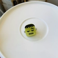 Detailed view of green glitter Frankenstein hair clip on a white ceramic plate - Mini Zombie