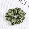 Olive green satin scrunchie with pleated silk texture on a minimalist magazine background - Grass Green