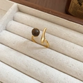 Vista macro de un anillo vintage dorado con piedra ojo de tigre en una bandeja de terciopelo - 19# Anillo de Ojo de Tigre Curvado Minimalista Dorado