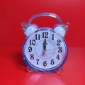 Blue transparent round quartz alarm clock with classic numerals on a red background - Blue Mini Round Alarm Clock