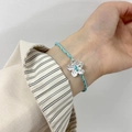 Detail des handgewebten blauen Blumenarmbands mit silbernem Anhänger am Handgelenk - 925er Silber / Gewebtes Blumenanhänger Armband (B3032-1)