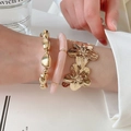 Dettaglio di un set di tre bracciali con fiori in metallo e perle di resina al polso. - Set di 3 pezzi / Oro e Rosa