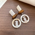Detail view of geometric drop earrings with wood beads and white resin on wooden surface - White/Brown Geometric Wood Splicing