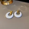Dettaglio degli orecchini retrò in resina bianca con perni dorati ed effetti di luce acquatica - Ago in Acciaio - Bianco