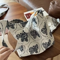 Dettaglio della borsa tote in tela color crema con stampa a farfalla vintage su tavolo - Borsa a Tracolla Grande Sottobraccio