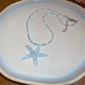 Primer plano de un colgante de estrella de mar azul sobre collar de cuentas azules y blancas - Collar con Colgante de Estrella de Mar de Resina con Cuentas de Semilla Azules
