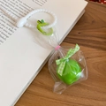 Detailed view of green apple keychain with white beads on an open vintage book - Green Apple Keychain Ornament