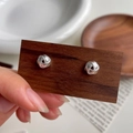 Detalle macro de pendientes de nudo en plata de ley S925 en tarjeta de madera - Plata 925 / Plata