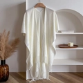 Primer plano de un chal de punto blanco crema con motivos calados y detalles de flecos - Talla única / Blanco