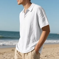 Close-up of men's white linen polo shirt with breathable fabric texture on a sunny beach - S / Tops / White