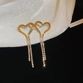 Makro-Detail goldener Herz-Ohrringe mit glitzernden Zirkonia-Quasten auf weichem Stoff - Gold-Klein (Silberstift)