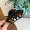 Gros plan de la pince à cheveux en résine marron foncé avec texture ambrée - Écaille de Tortue Brillante