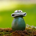 Vista macro di una divertente statua di rana verde con grandi occhi sul muschio - Rana Piccola