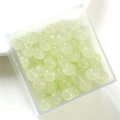 Close-up of pale yellow translucent glass beads in a transparent plastic container - Yellow Green Apple Bead