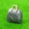 Miniature gray stone handbag pendant with golden metal handle on green grass background - Labradorite