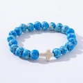 Detail view of blue turquoise stone beads bracelet with a white cross charm on a white background - Blue White Spotted White Cross Wood Bracelet