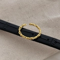 Macro view of golden braided chain knot ring on black leather strap with canvas texture - Adjustable Open / Gold
