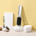 Portable silver folding hairbrush with mirror on stones against a yellow background - Spray Painted Silver (No Sticker)
