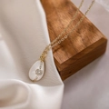 Dettaglio della collana dorata con ciondolo in smalto bianco su legno e seta - Bianco