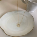 Elegante collana dorata con ciondolo a cerchio in cristallo scintillante su vassoio - Cerchio Rotondo