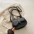 Chic black leather saddle bag with gold buckle and knotted strap on white blazer - Black