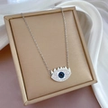 Macro shot of silver evil eye necklace with blue gemstone on white silk in jewelry box - Silver