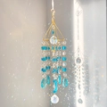 Detailed view of a gold suncatcher with K9 crystals casting rainbows on a white wall - Blue