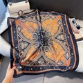 Detail of orange paisley silk scarf laid on white faux fur with luxury accessories - 70*70cm / Navy Paisley