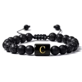 Détail macro du bracelet ajustable en pierre de lave noire avec perle dorée lettre C - Lettre C(C)