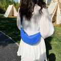 Blue nylon crescent crossbody bag worn by model in an outdoor camping setting - Blue